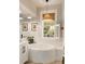 Bathroom with a soaking tub under a window with white shutters, pendant lighting, and neutral decor at 1012 Ashley Ave, Charleston, SC 29403