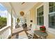 Front porch boasts ample space, a modern ceiling fan, and classic seating and a table at 1012 Ashley Ave, Charleston, SC 29403
