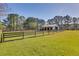 Horse barn with fence, surrounded by green pasture, under a bright blue sky at 1068 Witherbee Rd, Moncks Corner, SC 29461