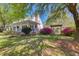 Landscaped yard featuring flowering shrubs, mature trees and a charming white home with a welcoming porch at 1068 Witherbee Rd, Moncks Corner, SC 29461