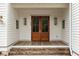 Inviting front porch with double wooden doors, brick steps, white siding and sconce lighting for a warm welcome at 1412 Jackson St, Mount Pleasant, SC 29464