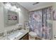 Well-lit bathroom with a decorative mirror, granite countertop, and floral shower curtain at 165 River Breeze Dr, Charleston, SC 29407