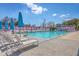 An outdoor swimming pool with lounge chairs, blue umbrellas, and tropical trees at 1656 Indy Dr, North Charleston, SC 29405