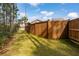 Fenced backyard with lush green grass and a mature tree border, offering privacy and natural beauty at 184 Clearblue Loop, Summerville, SC 29486