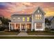 Charming two-story home with a welcoming front porch and beautiful landscaping against a picturesque sunset sky at 184 Clearblue Loop, Summerville, SC 29486