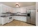 Functional kitchen with white cabinetry, gray countertops, stainless steel refrigerator, and tile floors at 203 Elliott Dr, Ladson, SC 29456