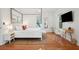 Bright bedroom features a four-poster bed, warm wood floors, a desk, and a mounted television at 217 E Huron Ave, Folly Beach, SC 29439
