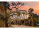 Charming stilt home with palm trees and string lights at sunset offers a relaxed coastal feel at 217 E Huron Ave, Folly Beach, SC 29439