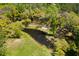 Aerial view of a tranquil pond, surrounded by verdant trees and expansive green fields, revealing a serene landscape at 2885 Plow Ground Rd, Johns Island, SC 29455