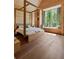 Spacious light-filled bedroom with wood-paneled walls, canopy bed, and a window seat overlooking the wooded property at 2885 Plow Ground Rd, Johns Island, SC 29455