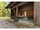 View of the open air garage with multiple bays, ATVs, lawnmower, small boat and work benches, and horizontal wood planking at 2885 Plow Ground Rd, Johns Island, SC 29455
