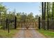 Stately wooden gate entrance with a gravel driveway, lined by manicured fencing and lush greenery at 2885 Plow Ground Rd, Johns Island, SC 29455