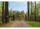 Gravel driveway with a wooden gate, framed by tall trees and fencing, providing privacy and security at 2885 Plow Ground Rd, Johns Island, SC 29455