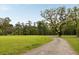Scenic view of a gravel road winding through a lush, green field with mature trees and a clear blue sky at 2885 Plow Ground Rd, Johns Island, SC 29455