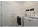 Functional laundry area features white washer and dryer, storage shelves, and door to the exterior at 5224 Stonewall Dr, Summerville, SC 29485