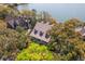 An aerial view featuring the home's charming architecture nestled among lush trees and landscaping with views of the water at 66 New Settlement Rd, Kiawah Island, SC 29455