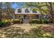 Charming two-story home featuring a welcoming front porch, complemented by mature trees and lush landscaping at 66 New Settlement Rd, Kiawah Island, SC 29455