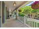 Spacious covered front porch with hanging floral baskets, white railing, and views of lush greenery at 66 New Settlement Rd, Kiawah Island, SC 29455