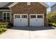 A brick garage with two white doors and black hardware. Nice clean concrete apron at 711 Farm Cottage Ln, Charleston, SC 29412