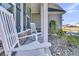 Close-up of the front porch featuring classic white rocking chairs, stone detailing, and manicured landscaping at 106 Lakelyn Rd, Moncks Corner, SC 29461