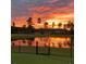 A pond reflects an orange sunset and surrounding trees behind a black fence at 110 Haverhill St, Summerville, SC 29486