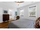 Well-lit bedroom featuring a ceiling fan, light wood floors, and a view to the bathroom at 1130 5Th Ave, Charleston, SC 29407