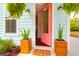Charming home featuring an open pink front door, complemented by potted plants and fern hangings at 1130 5Th Ave, Charleston, SC 29407