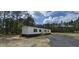 Beautiful single-story home with white siding and a brick foundation; a gravel driveway leads to a wooden fence at 115 Sandy Oaks Ln, Cross, SC 29436