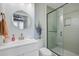 Modern bathroom with a glass-enclosed shower, round mirror, and white vanity with a white countertop at 1157 King St, Charleston, SC 29403