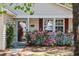 Close-up of the front door area with storm door, sidelight, shutters, and lush, pink flower bushes at 1411 River Front Dr, Charleston, SC 29407