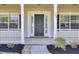 Close-up of a charming front porch with decorative columns, a black front door, and manicured landscaping, creating a welcoming entry at 150 Sugar Magnolia Way, Charleston, SC 29414