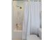 Shower with white tiles, green dots, shower head, and white curtain at 1651 Atlantic Ave, Sullivans Island, SC 29482