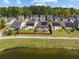 An aerial view of a neighborhood with well-maintained lawns and a community pond and forest in the background at 187 Brittondale Rd, Summerville, SC 29485
