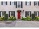 Inviting facade with a red door, black shutters, and manicured garden beds enhancing its curb appeal at 2 Bedons Aly, Charleston, SC 29401