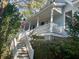 Two-story home with a welcoming porch, surrounded by lush greenery and mature trees at 2 Wills Way, Isle of Palms, SC 29451