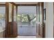 View through open doors to a covered porch with a wooden floor and a white railing showcasing trees beyond at 2 Wills Way, Isle of Palms, SC 29451