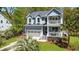 Home exterior showcasing a two-car garage, double porches, well-maintained lawn, and mature palm tree at 2111 Nicholas David Path, Johns Island, SC 29455