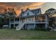 Beautiful two-story home with wraparound porch and staircase, set against a colorful sunset sky at 2312 Rushland Landing Rd, Johns Island, SC 29455