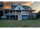 Beautiful two-story home with wraparound porch and staircase, set against a colorful sunset sky at 2312 Rushland Landing Rd, Johns Island, SC 29455
