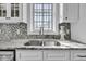 Bright kitchen with stainless steel sink, granite countertops, mosaic tile backsplash, and ample natural light from a large window at 2340 Salt Wind Way, Mount Pleasant, SC 29466