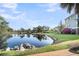 Picturesque view of a tranquil pond reflecting trees with lush green grass and blooming flowers at 2340 Salt Wind Way, Mount Pleasant, SC 29466