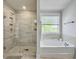 Bright bathroom with a glass shower, white soaking tub under a window, and neutral colored tile at 2823 Dearmin Dr, Mount Pleasant, SC 29466