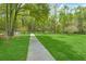Lush backyard featuring a stone pathway, vibrant greenery, and mature trees, creating a serene outdoor space at 3060 Bohicket Rd, Johns Island, SC 29455