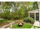 Landscaped backyard retreat with fire pit, stone pathway, mature trees, and lush surroundings at 3060 Bohicket Rd, Johns Island, SC 29455