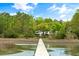 Waterfront home with a private wooden dock leading to a tranquil lake surrounded by lush greenery at 3060 Bohicket Rd, Johns Island, SC 29455