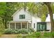 Charming white farmhouse featuring a screened porch, fire pit, and lush landscaping at 3060 Bohicket Rd, Johns Island, SC 29455