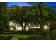 Stately waterfront home with dock, lush landscaping, and inviting, illuminated windows at dusk at 3060 Bohicket Rd, Johns Island, SC 29455