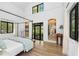 Bright main bedroom features a canopy bed, hardwood floors and black framed doors to a patio at 3060 Bohicket Rd, Johns Island, SC 29455