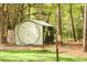 Exterior view of a white storage shed with dark trim in a wooded area at 3060 Bohicket Rd, Johns Island, SC 29455