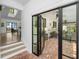 Sunroom with black framed doors to brick patio, flowing to open floor plan at 3060 Bohicket Rd, Johns Island, SC 29455